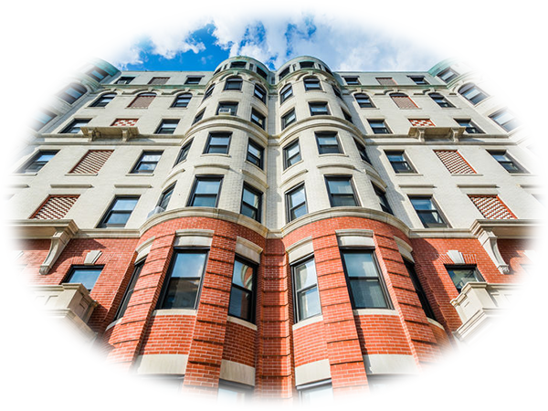 Low-angle view of a multi-story brick and stone apartment building with rounded windows and decorative details.